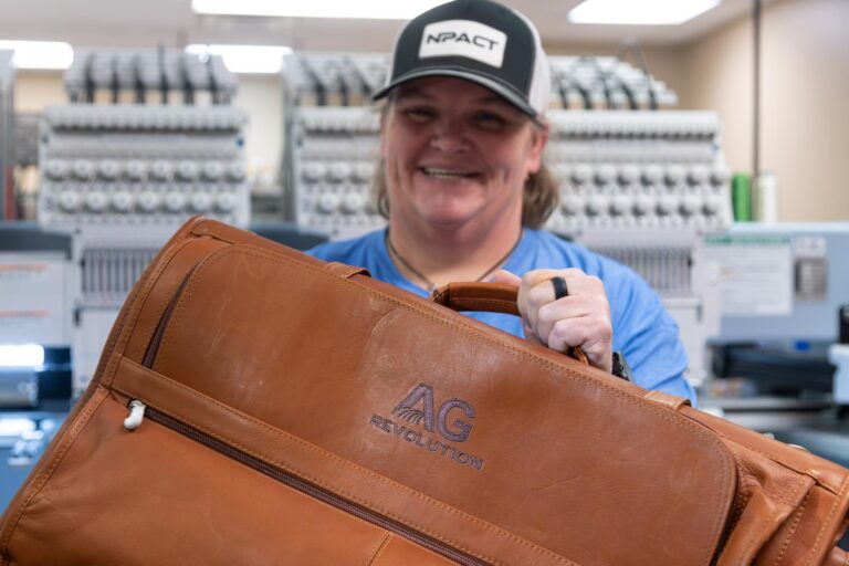 Smiling employee holding a leather embroidered bag